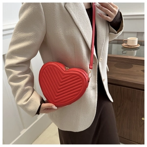 Vue détaillée du sac à bandoulière rouge en forme de cœur avec surpiqûres en V chic