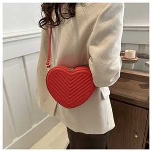 Détail du sac à bandoulière rouge en forme de cœur avec surpiqûres en V et métal doré
