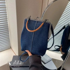 Detail of blue denim kiss-lock handbag with silver frame and leather handles