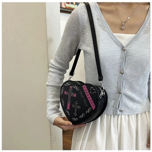Détail d'un sac bandoulière en forme de cœur avec motif gothique et décorations