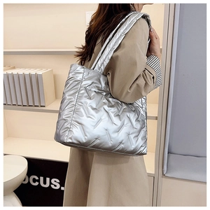 Vue latérale d'un grand sac cabas argenté matelassé porté par un mannequin en intérieur