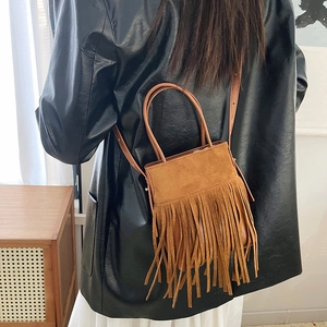 Bohemian brown suede tassel bucket bag shown on a model with long fringes and strap