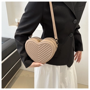 Détail du sac à bandoulière matelassé en forme de cœur beige avec ferrures dorées