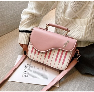 Detail of piano key pattern and treble clef embroidery on a pink crossbody bag