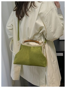 Vue détaillée du sac coquille en daim vert avec poignée en bois et cadre doré chic