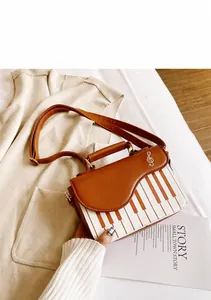 Detailed close-up of yellow-brown piano keyboard crossbody bag with golden treble clef hardware