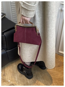 Détail du sac en daim bordeaux avec cadre métallique vintage et poignée en bois