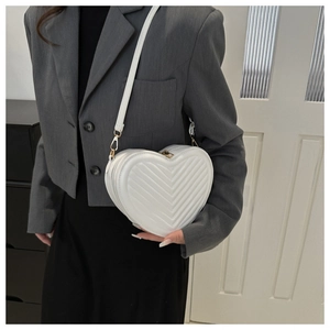 Détail du sac blanc en forme de cœur avec matelassage en V et finitions dorées