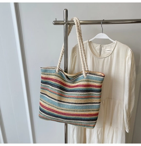 Détail du cabas tissé aux rayures colorées suspendu avec une robe blanche
