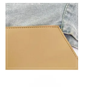 Detail showing the fine stitching on light blue denim and tan leather laptop bag surfaces