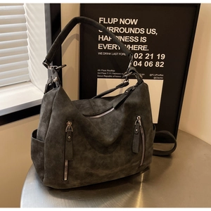 Macro shot of dark grey hobo bag with matte suede texture and decorative metal zippers