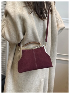 Modèle portant un sac coquillage en daim bordeaux avec poignée en bois et surpiqûres