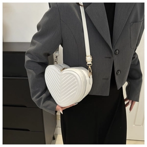 Gros plan du sac bandoulière blanc en forme de cœur avec matelassage en V et zip doré