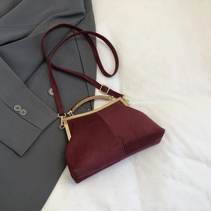 Détail du sac coquille bordeaux avec texture en velours et fermoir en métal doré