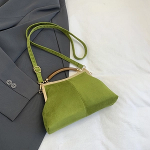 Détail du sac coquille en daim vert avec poignée en bois et fermoir vintage en métal