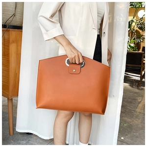 Detail of the elegant orange-brown PU leather tote featuring a silver oval metal handle