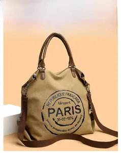 Detail of khaki canvas tote bag with brown leather handles and adjustable crossbody strap
