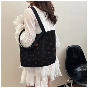 Detail of strawberry embroidery on black corduroy tote bag with leather logo tag