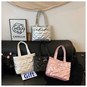 Sacs cabas matelassés en argent métallisé, blanc, noir et rose sur un banc en cuir