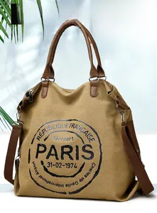 Detail of canvas tote bag with retro Paris stamp print and brown faux leather handles