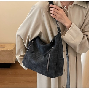 Detail of matte black suede tote bag showing metallic zipper pockets and soft texture