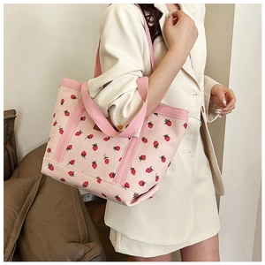 Detail of pink corduroy tote bag featuring red strawberry print and soft striped texture