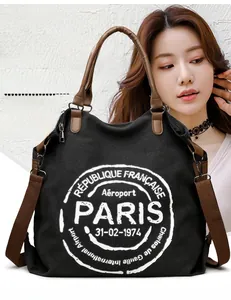 Close-up of black canvas tote with Paris print, leather handles and strap details