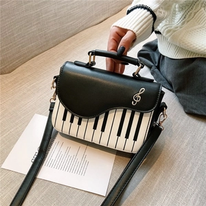 Elegant black and white piano key crossbody bag with treble clef metal hardware