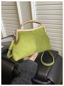 Détail du sac coquille en daim vert avocat avec cadre en métal et poignée en bois