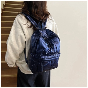 Détail d'un sac à dos matelassé bleu avec bretelles rembourrées et fini métallique