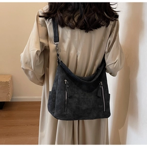 Detail of dark grey hobo bag showing matte suede texture and metal zippers
