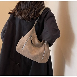 Detail of large brown hobo bag with dual vertical zippers and wide shoulder strap