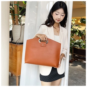 Detail of laptop handbag showing silver metal ring handle and textured brown PU leather