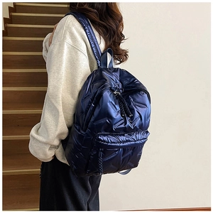 Détail d'un sac à dos matelassé bleu marine avec fini métallisé et tirettes tissées