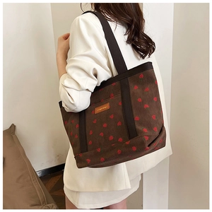 Detail of corduroy tote bag showing strawberry prints and textured shoulder strap