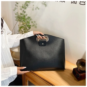 Detail of minimalist black PU briefcase with silver oval metal handle and matte texture