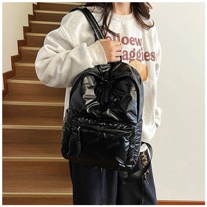 Détail d'un sac à dos matelassé noir avec texture brillante et tirette de zip tissée