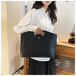 Detail view of a large black PU leather laptop bag with round silver metal top handles