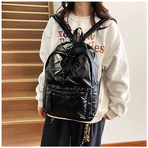 Vue détaillée du sac à dos matelassé noir brillant avec bretelles et poche zippée