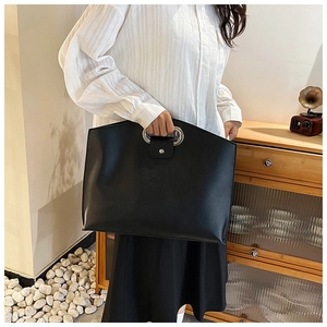 Detail of elegant black PU leather tote with large silver metal ring handles for business