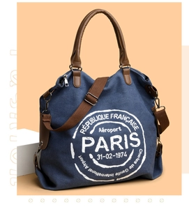 Detail of blue canvas tote bag with brown leather handles and vintage Paris airport print