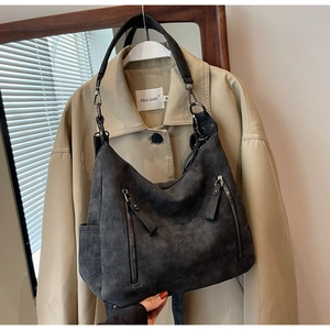 Close-up of charcoal grey faux suede tote bag featuring dual front zippers and wide straps