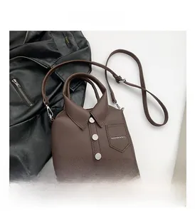 Detailed view of dark brown lychee leather bag in shirt shape with decorative buttons