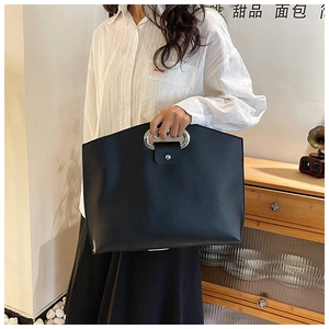 Detail of minimalist black PU leather laptop tote with silver oval metal cutout handle