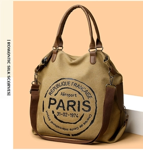 Detailed close-up of retro khaki canvas tote bag with brown leather handles and vintage print