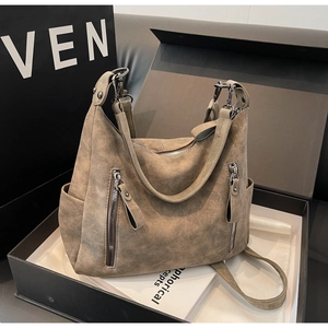 Close-up of large coffee brown suede tote bag with symmetric zippers in a luxury gift box