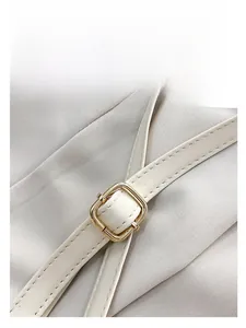 Detail of adjustable white leather strap with polished gold buckle and fine stitching