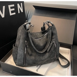 Detail of dark grey textured tote bag with silver zippers inside a gift box