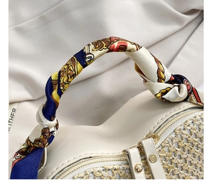 Detail view of woven heart beach bag with vibrant silk scarf handle and dual zippers