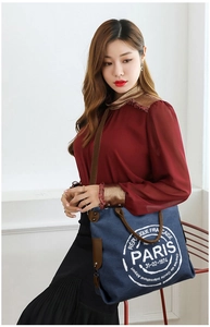 Detail of navy canvas tote bag featuring brown leather straps and vintage Paris logo print